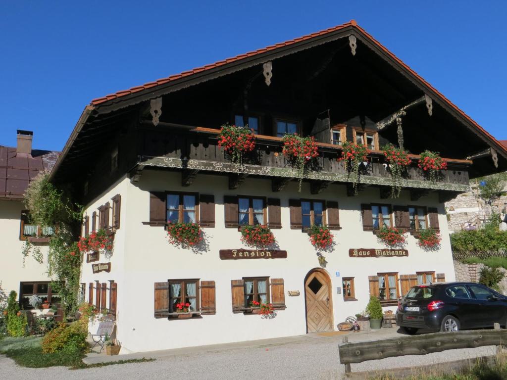 ein weißes Gebäude mit Blumenkästen an den Fenstern in der Unterkunft Pension Marianne in Inzell