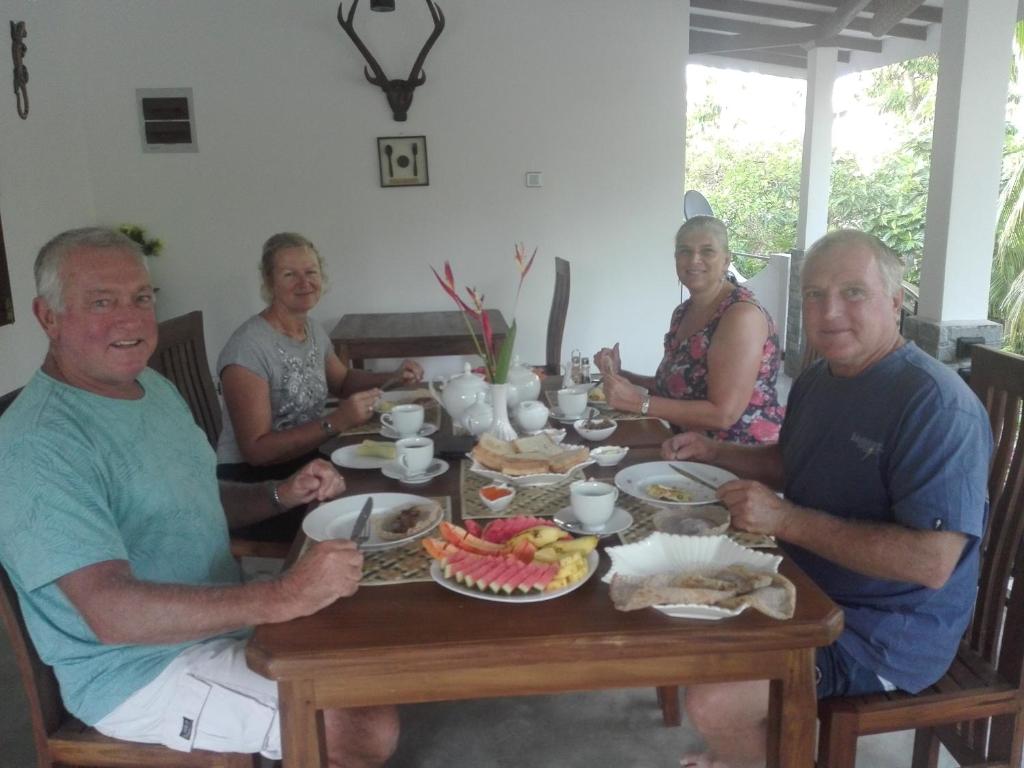 a group of people sitting around a table eating food at Neo Grand Villa in Galle