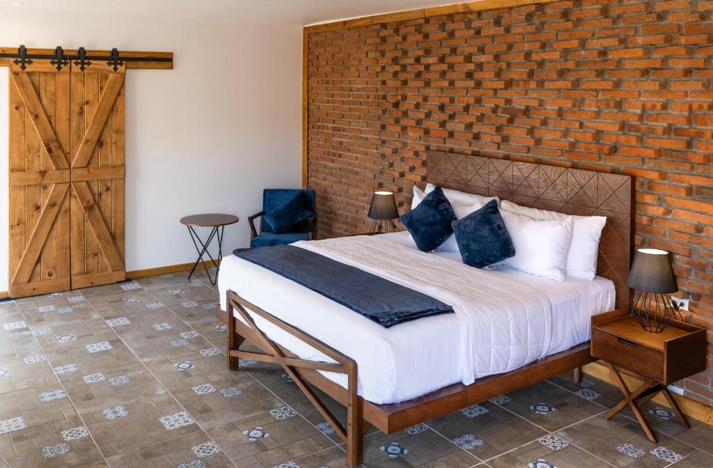 1 dormitorio con cama y pared de ladrillo en OJO AZUL RESORT, en Valle de Guadalupe