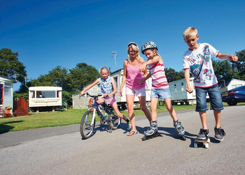 un grupo de tres niños parados junto a una bicicleta en Country Coastal Holidays - Families and Couples only en New Romney