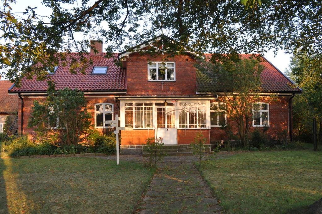 a red brick house with a tree in front of it at Villa Sandby B&B in Borrby