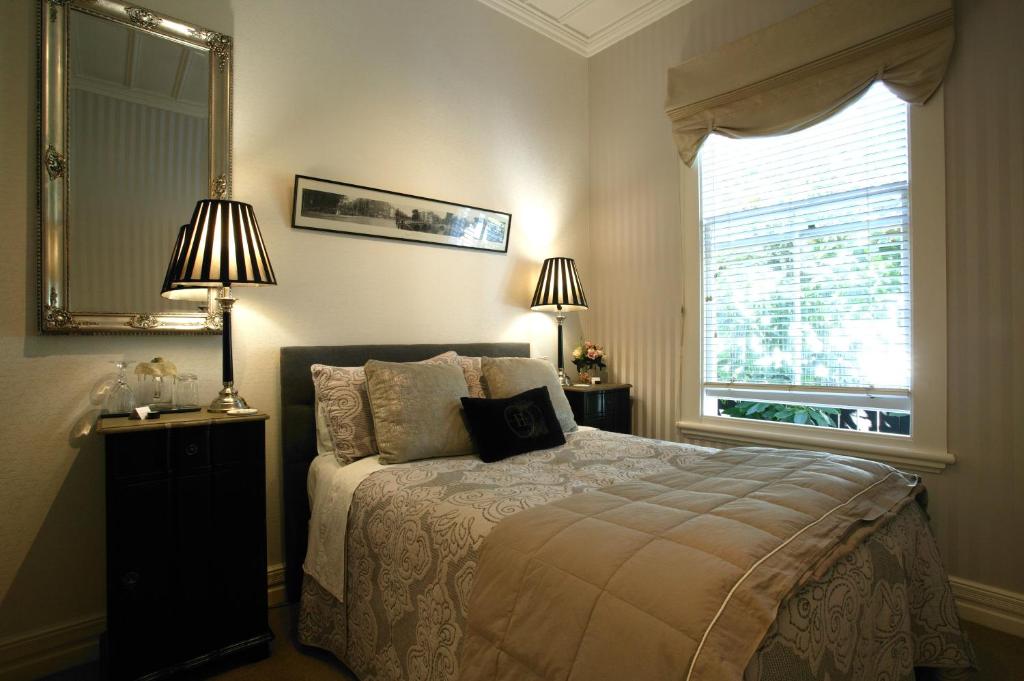 a bedroom with a bed with two lamps and a window at Eden Park Bed And Breakfast Inn in Auckland