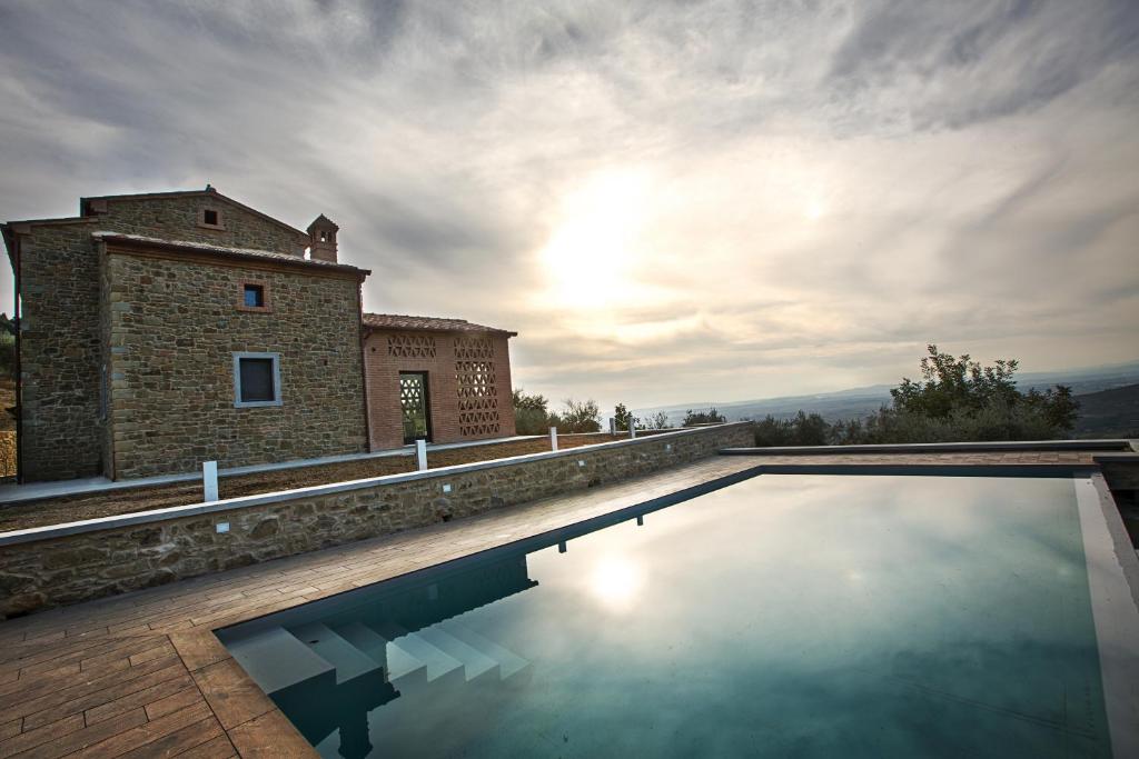 a house with a swimming pool in front of a building at Fonte al Vento in Cortona