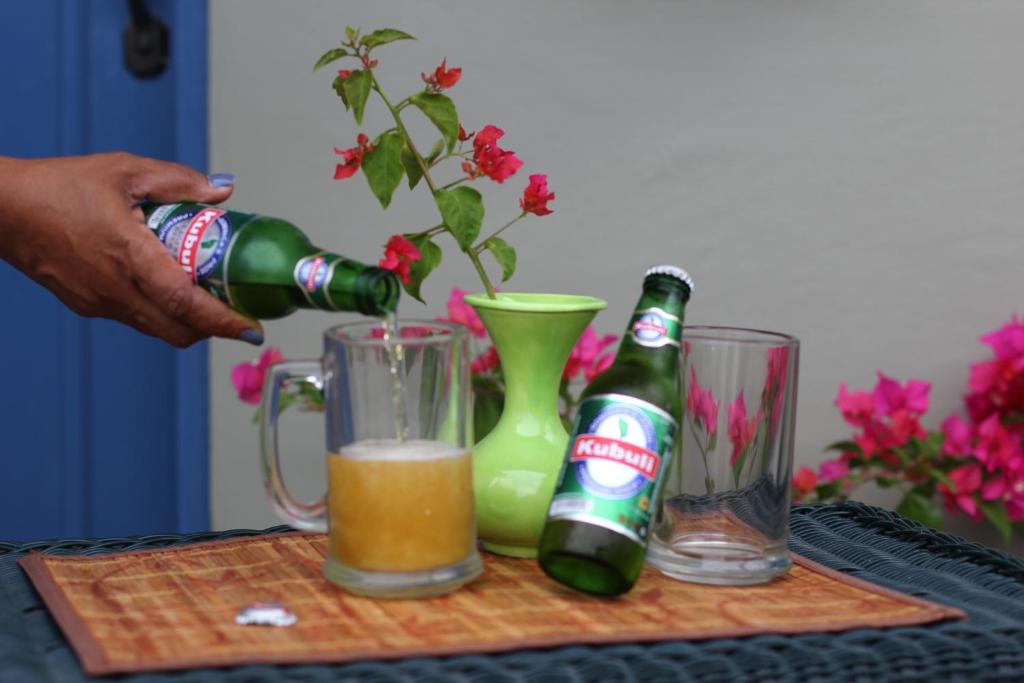 a person pouring a bottle of beer into a drink at The AnSwin Apartment in Roseau