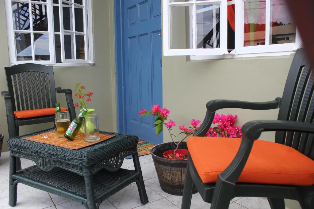 a patio with two chairs and a table and a blue door at The AnSwin Apartment in Roseau