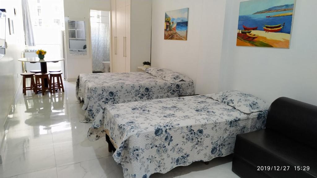 een kamer met drie bedden en een tafel erin bij Quitinete Centro de Guarapari. in Guarapari