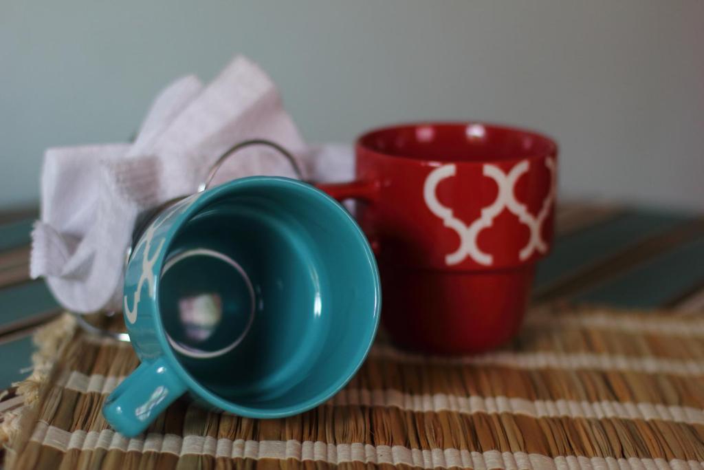 a green coffee mug and a red cup on a table at The AnSwin Apartment in Roseau