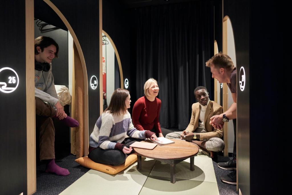 a group of people sitting around a table in a room at Resol Poshtel Tokyo Asakusa in Tokyo