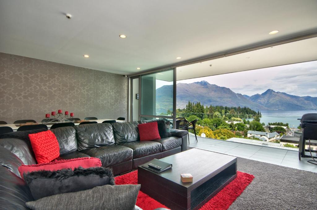 a living room with a leather couch and a large window at Lakeview 5BR Apartment Walk to Town in Queenstown