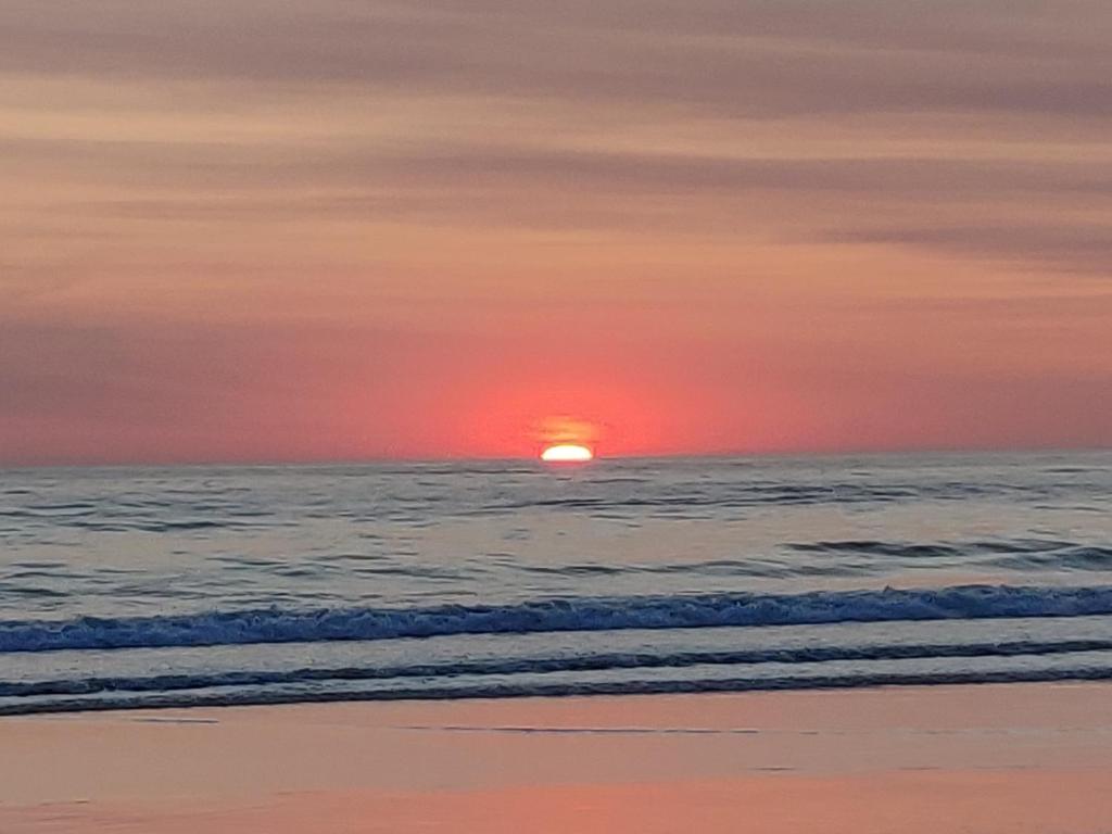 um pôr do sol na praia com o oceano em Chalet Utama em Punta del Este