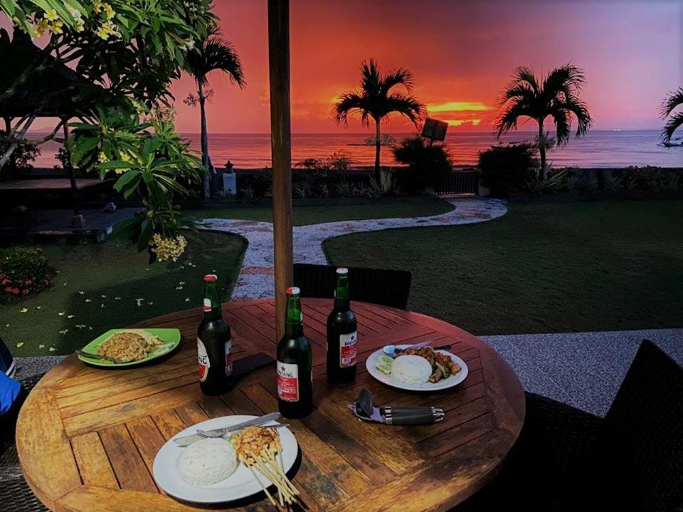 una mesa de madera con platos de comida y botellas de vino en Blue Gecko West Bali, en Penginuman