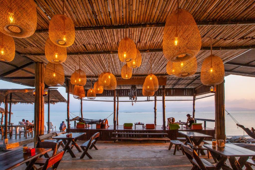 un restaurant avec des tables, des chaises et des lumières dans l'établissement The Cosy Koh Phangan, à Thongsala