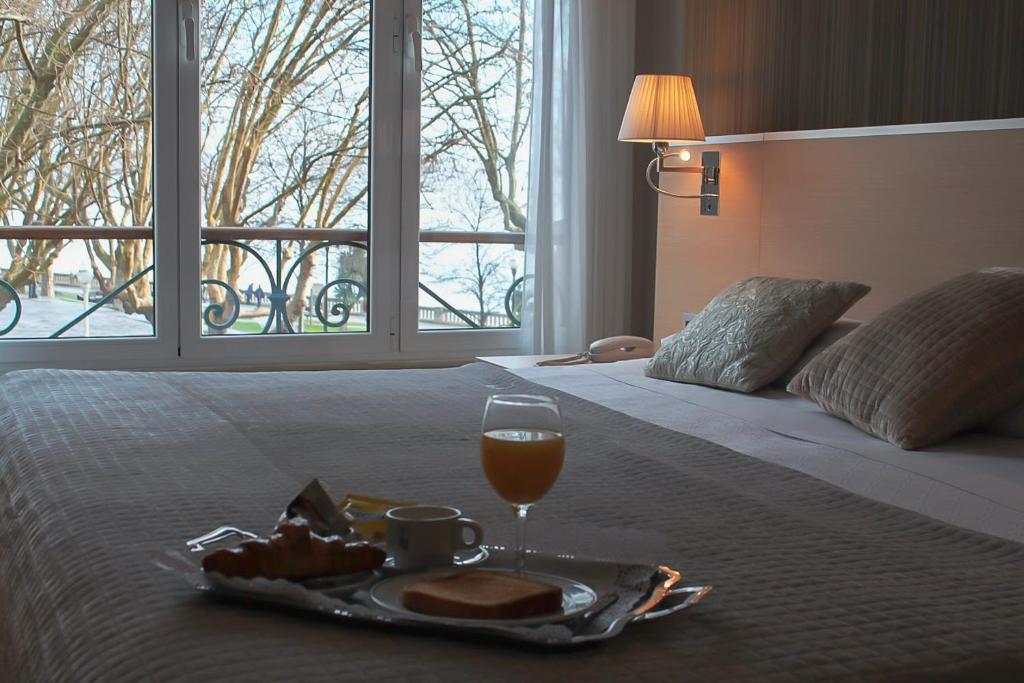 ein Tablett mit Essen und ein Glas Wein auf dem Bett in der Unterkunft Hotel Asturias in Gijón