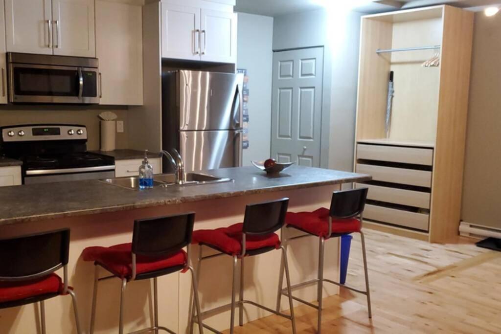 a kitchen with a counter with red chairs at a counter sidx at 1-Bedroom Apartment Bellisimo AG by Amazing Property Rentals in Gatineau