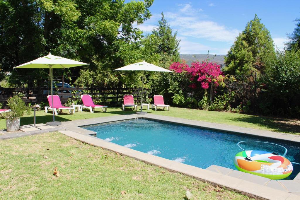 a swimming pool with chairs and umbrellas in a yard at Nuwerus Lodge Paarl in Paarl