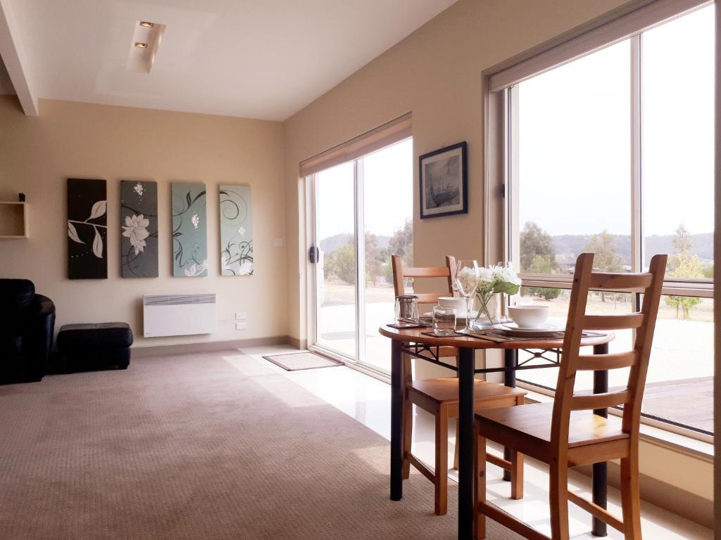 a dining room with a table and chairs and large windows at Couples Retreat with Mountain View Near Hobart in Sandford