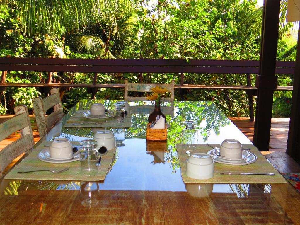 a glass table with plates and mugs on it at Pousada Naiepe in Fernando de Noronha