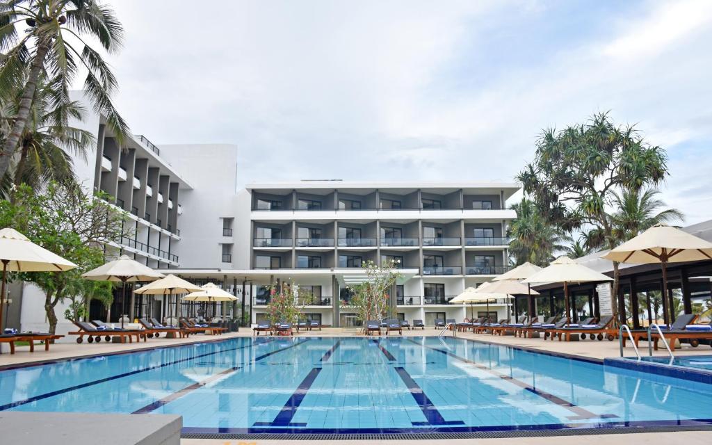 a swimming pool with a hotel in the background at Goldi Sands Hotel in Negombo