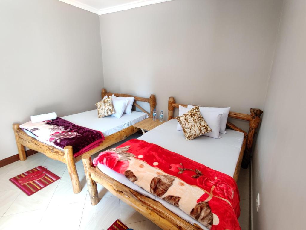 2 Betten in einem Zimmer mit roten und weißen Decken in der Unterkunft Wanyama B&B in Arusha