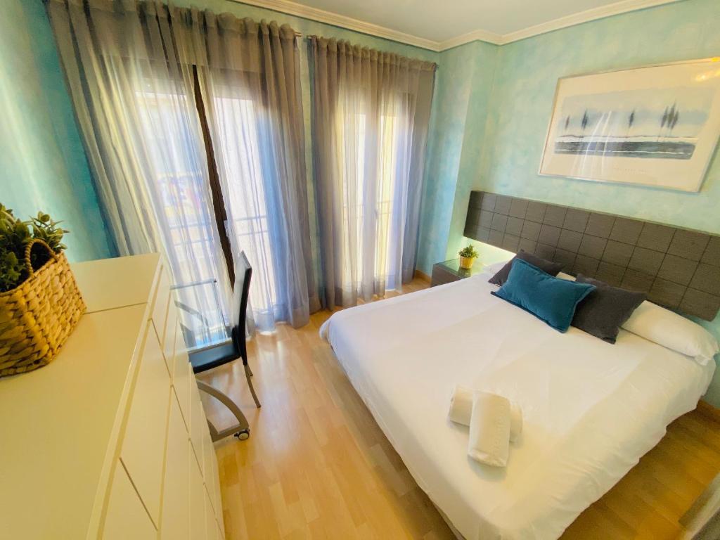 una camera da letto con un letto bianco, pareti blu e una finestra di El Rincón de las Armas a Saragozza
