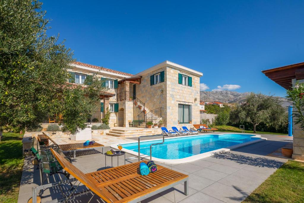 ein großes Haus mit Pool im Hof in der Unterkunft Villa Domnius in Žrnovnica