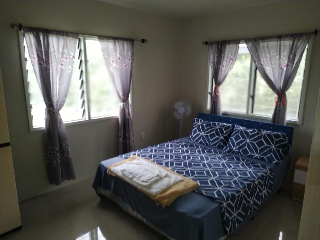 アピアにあるKuinis Guesthouseの青いベッドと2つの窓がある寝室