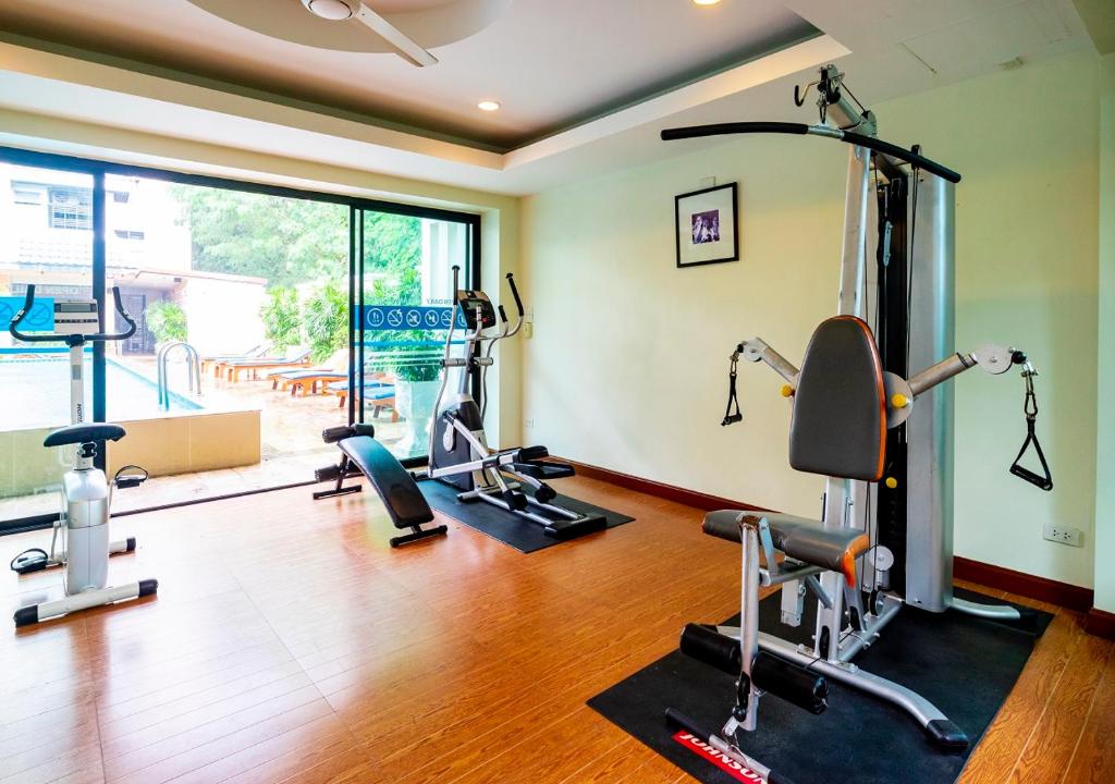 A bright hotel gym with cardio machines and a multi-station weight machine beside full-height windows.