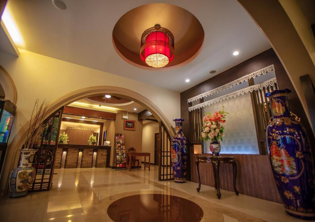 An ornate lobby features a red hanging lantern, ceramic vases, and a reception area beyond an archway.
