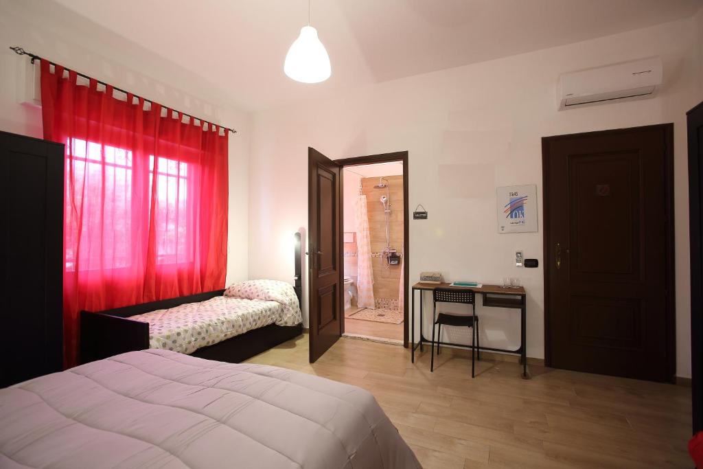 una camera con due letti e una tenda rossa di Rooms Project B&B a Capoterra