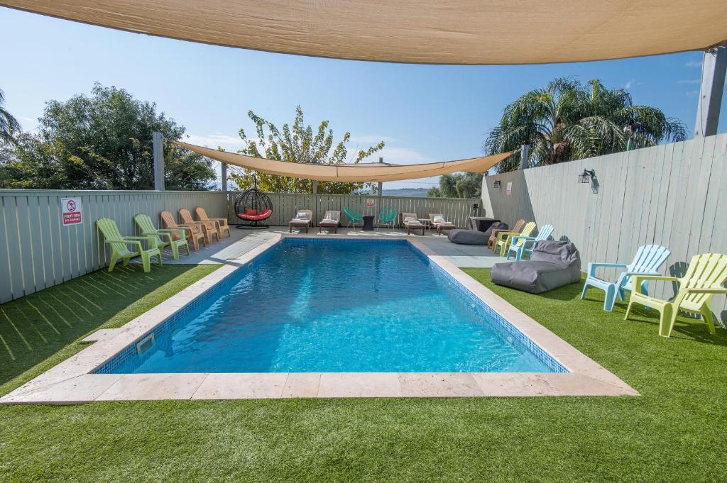 a swimming pool in a yard with chairs and a fence at Nof Kinneret Cabins in Had Nes