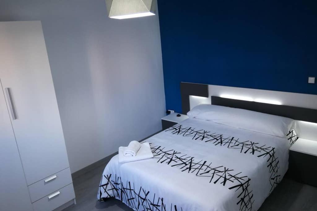 - une chambre avec un lit blanc et un mur bleu dans l'établissement Apartamento Centrico , Wifi + Desayuno, à Logroño