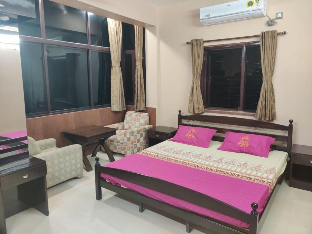 um quarto com uma cama com lençóis roxos e uma cadeira em Sukhmani Homestays em Calcutá