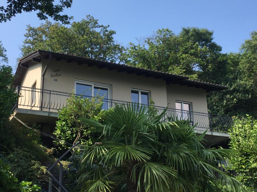 una casa con balcón en medio de árboles en Casa Barbara - eine Oase der Ruhe oberhalb des Lago di Lugano en Carona