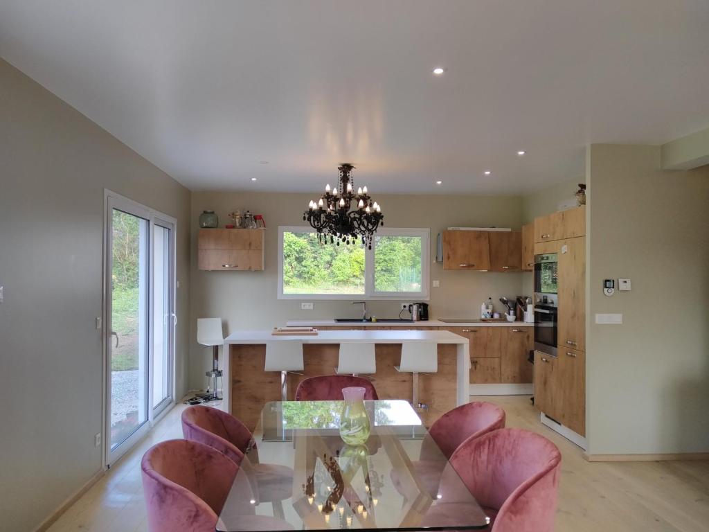 une cuisine avec une table en verre et des chaises roses dans l'établissement La villa d à côté Marigny, Lac de Chalain, à Mont-sur-Monnet