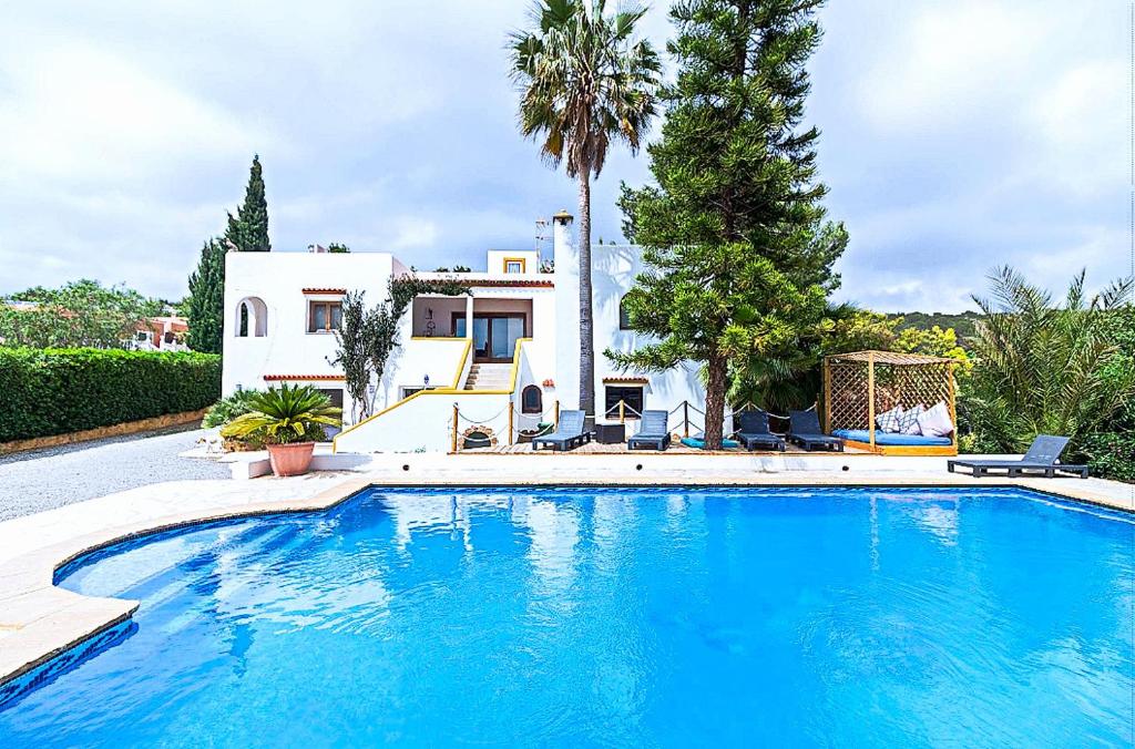 una grande piscina blu di fronte a una casa di Ca n'Estrella a Santa Gertrudis de Fruitera