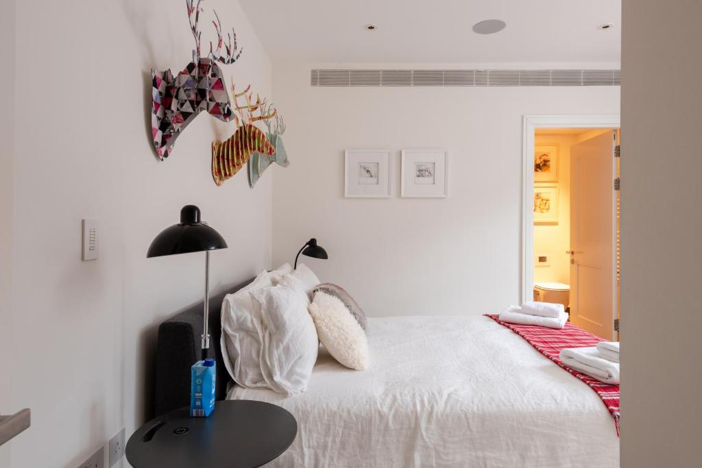 een witte slaapkamer met een bed en een tafel bij Rock Paper Scissors in Londen