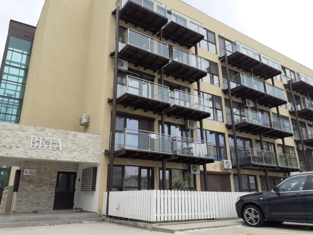an apartment building with balconies and a car parked in front at Beta Residence Saturn in Mangalia