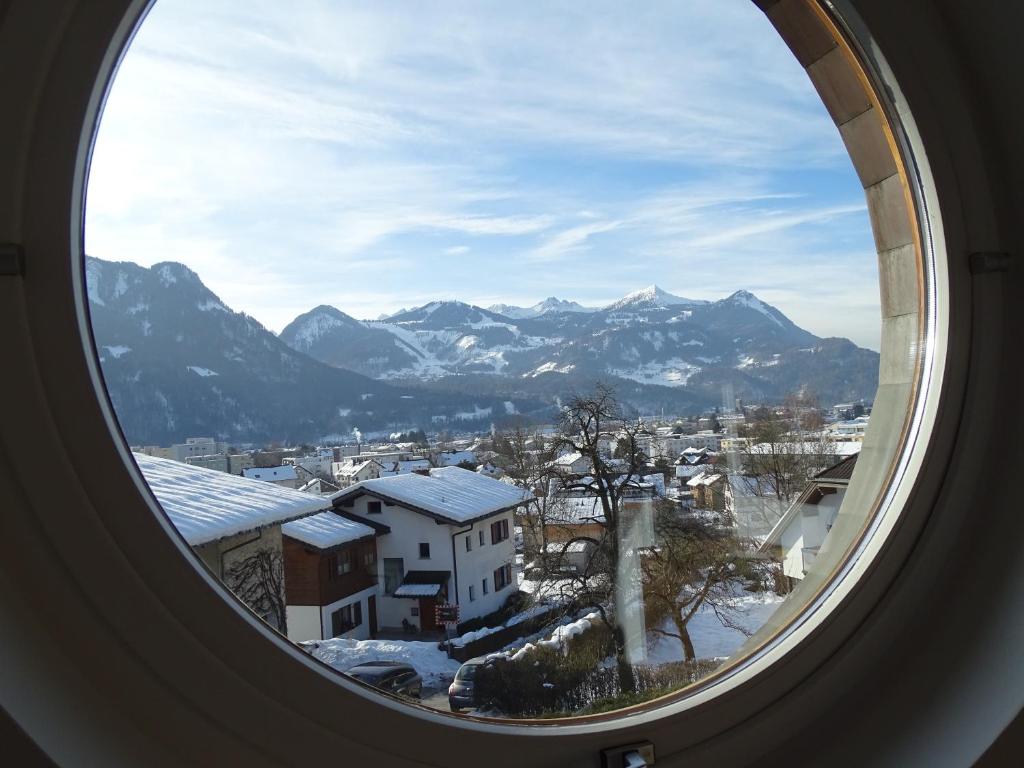a round window with a view of a city and mountains at Appartement Christiane in Bludenz