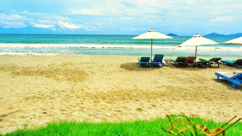 - une plage avec des chaises et des parasols et l'océan dans l'établissement Seasnails Homestay, à Hội An