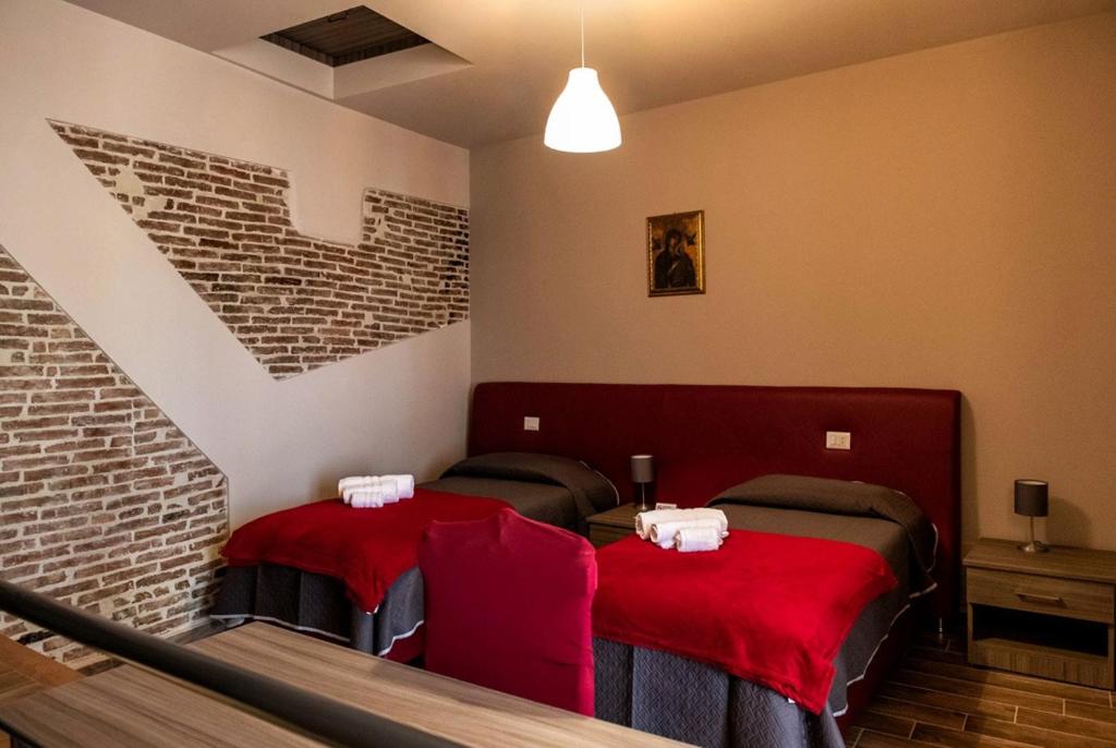 two beds with red covers in a room with stairs at Il Carro Comfortable Rooms in San Giovanni Gemini