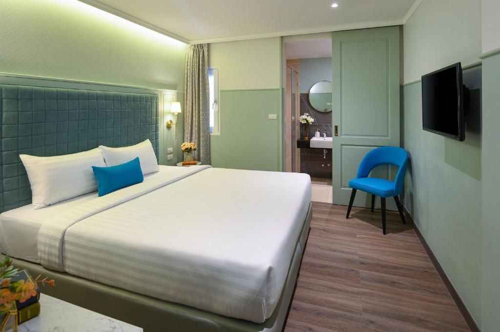 um quarto com uma cama grande e uma cadeira azul em The Mulberry Bangkok Khaosan Road em Banguecoque