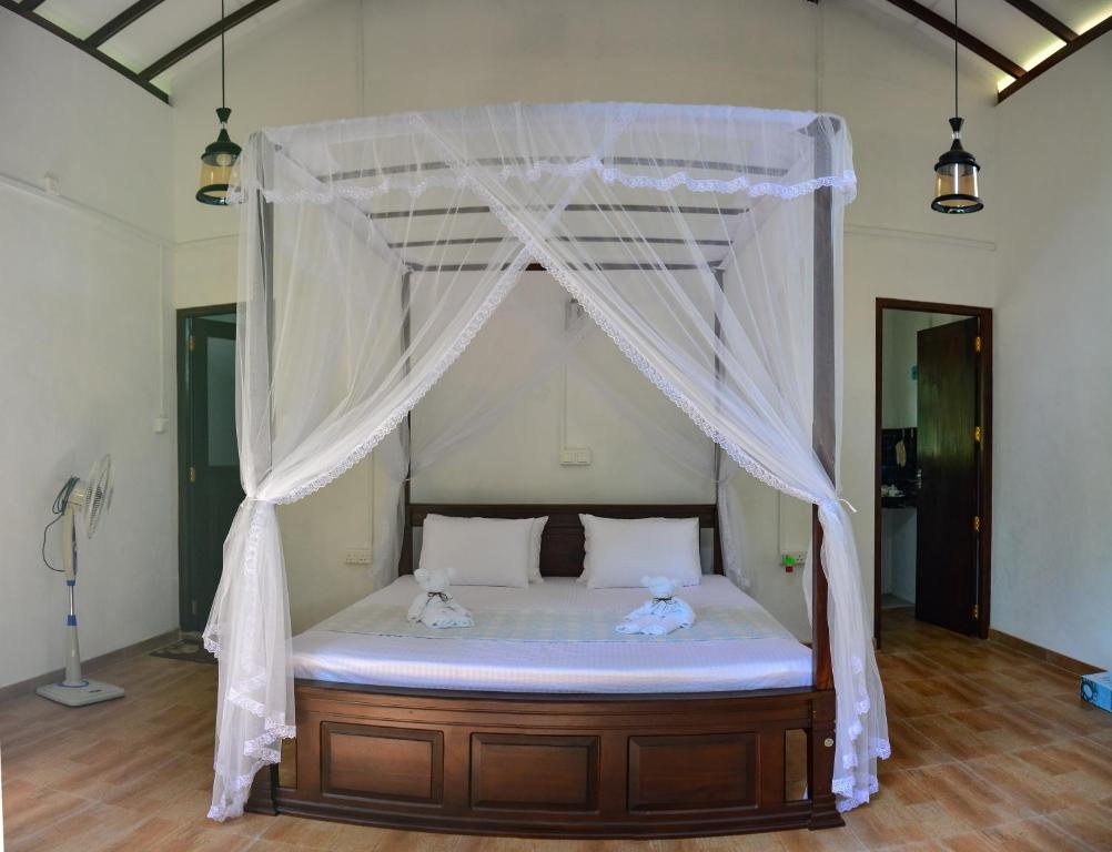 a bedroom with a canopy bed with two teddy bears on it at Groot in Hikkaduwa