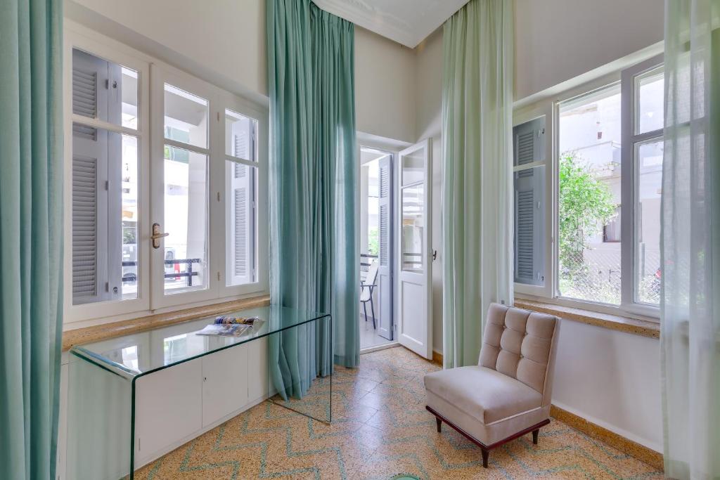 Zimmer mit Fenstern, einem Glasschreibtisch und einem Stuhl in der Unterkunft Samouil Apartment, 40 meters from the beach in Chania