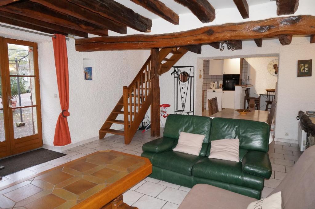 a living room with a green couch and a staircase at Fontaine Gargot - La sapinière 5p in Poligny