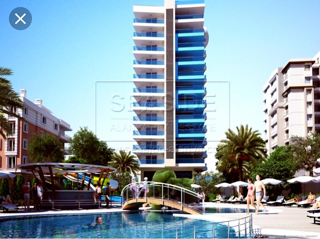 Blick auf einen Pool mit einem Gebäude in der Unterkunft Empire Residence Alanya/Mahmutlar 50m от моря in Alanya