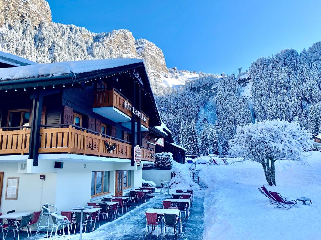 a building with tables and chairs in the snow at Hameau des Prodains - Hôtel in Morzine