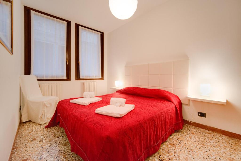 een slaapkamer met een rood bed en 2 handdoeken erop bij Rialto Dream - Wifi in Venetië