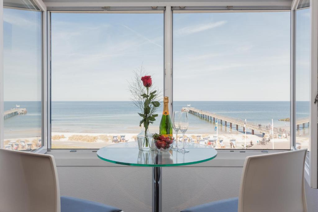 einen Tisch mit einer Vase aus Blumen und Blick auf den Strand in der Unterkunft Ostseemeerblick in Schönberger Strand