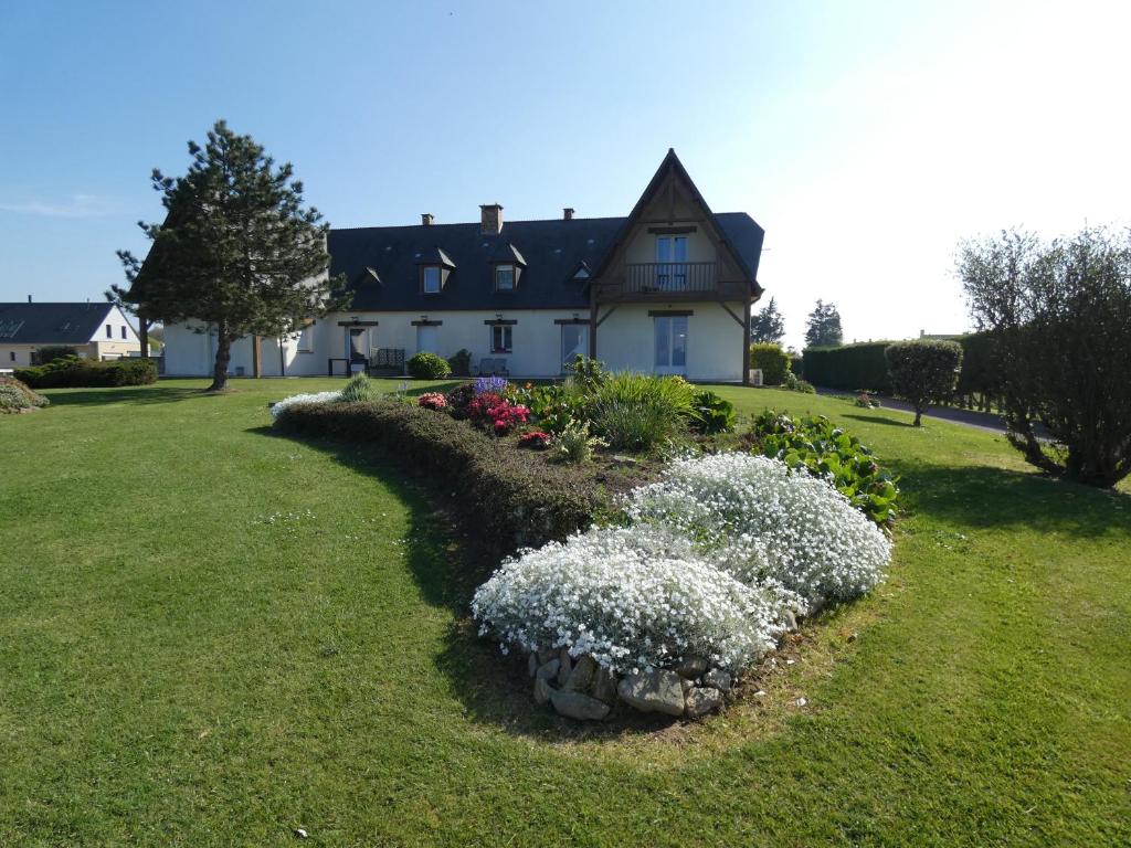 une maison avec un jardin fleuri dans la cour dans l'établissement Omaha gîtes, à Vierville-sur-Mer