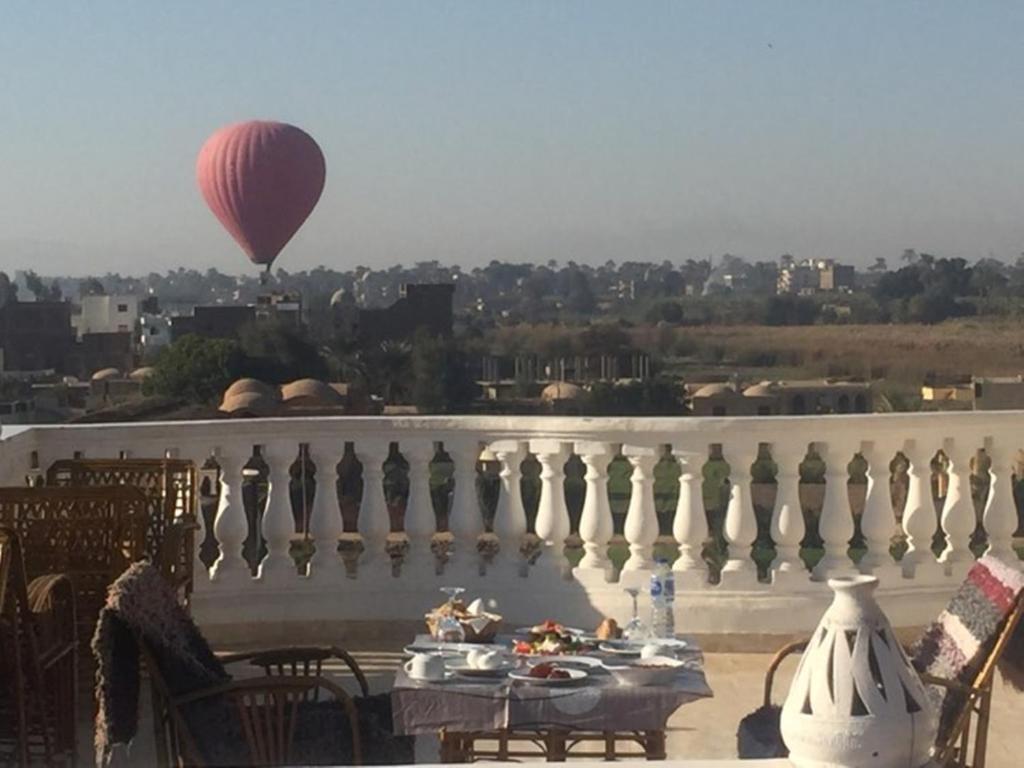 a hot air balloon flying over a balcony with a table at Gold Ibis Hotel in Luxor